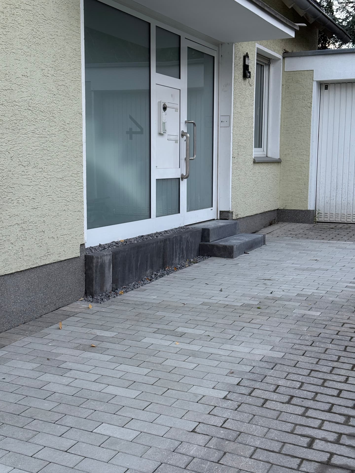 Neu verlegte Pflasterfläche am Hauseingang mit Stufenanlage und Kiesstreifen